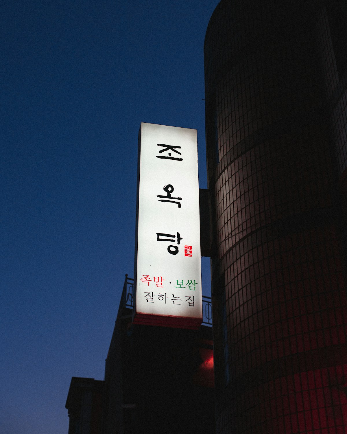 복잡한 서울의 밤거리에서 네온사인 빛을 받으며 스마트폰을 보고 있는 사람의 극사실적인 옆모습
