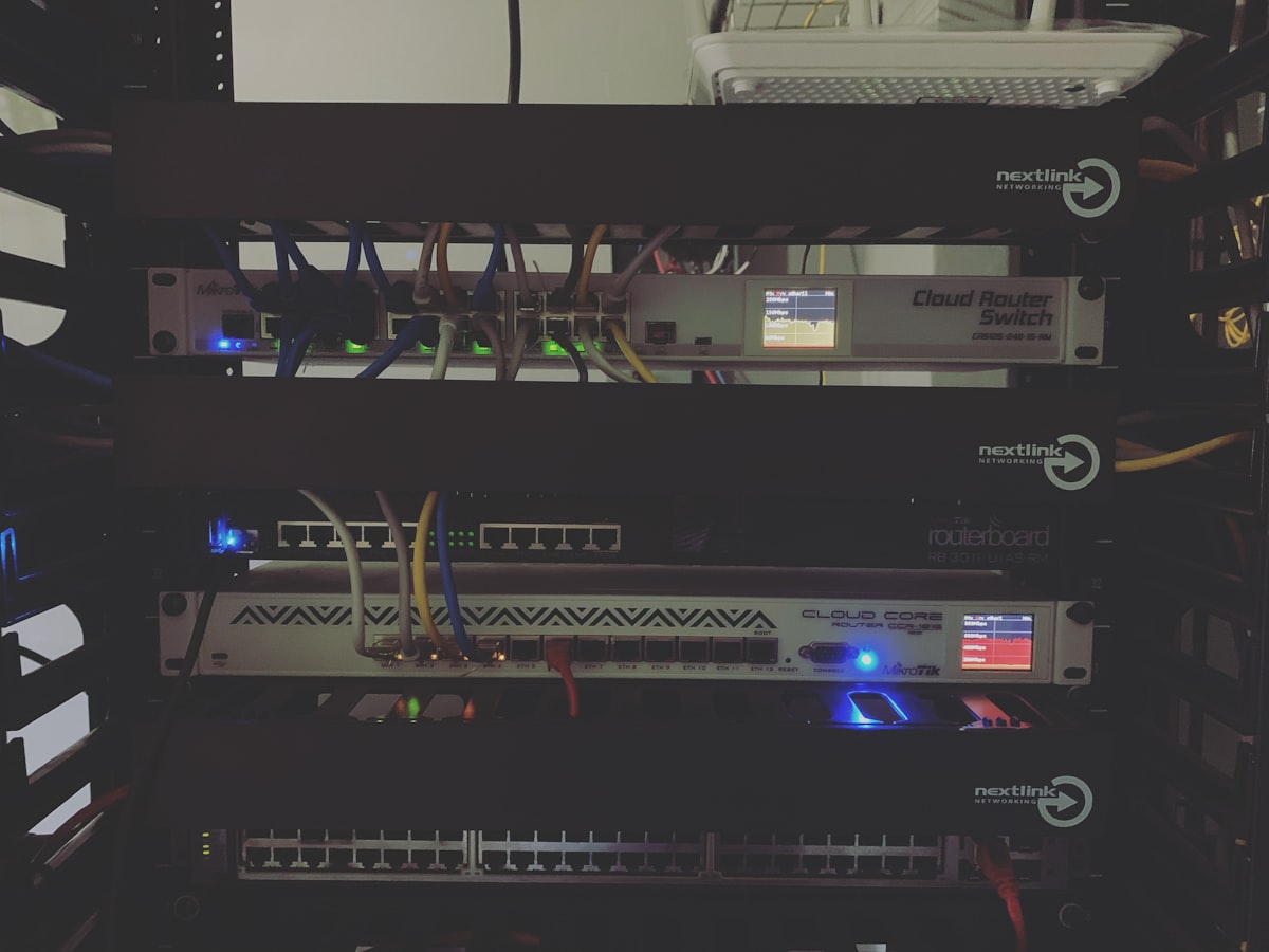 복잡한 코드가 적힌 화면과 여러 국가의 지도가 띄워진 모니터 앞에서 VPN 서버를 선택하는 손가락