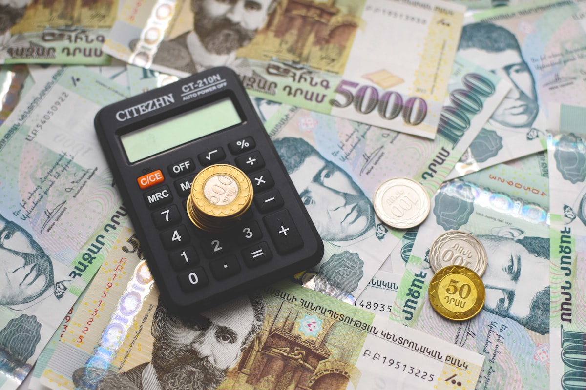 노트북 화면 앞에 계산기와 환율 차트가 띄워져 있고 사용자가 복잡한 수식을 정리하고 있는 클로즈업 샷