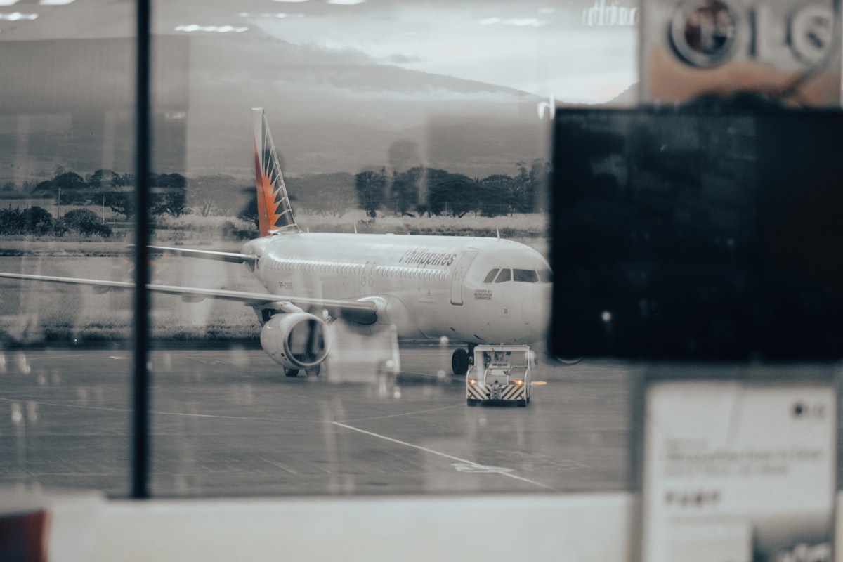 현대적인 공항 라운지에서 맥북을 펼쳐놓고 여행 일정을 정리하며 결제 내역을 검토하는 비즈니스맨